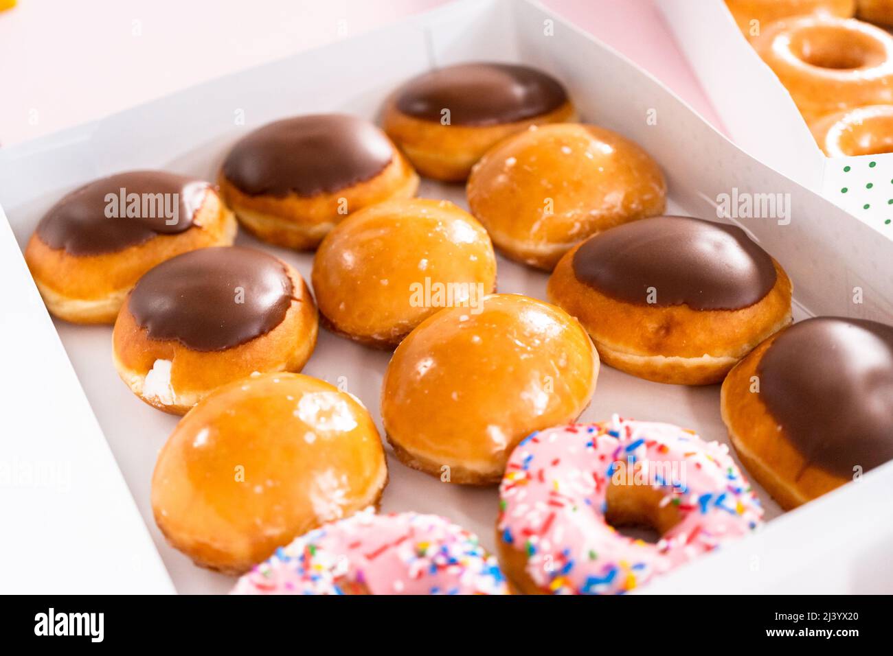 Variety of store-bought doughnuts in a white paper box Stock Photo - Alamy