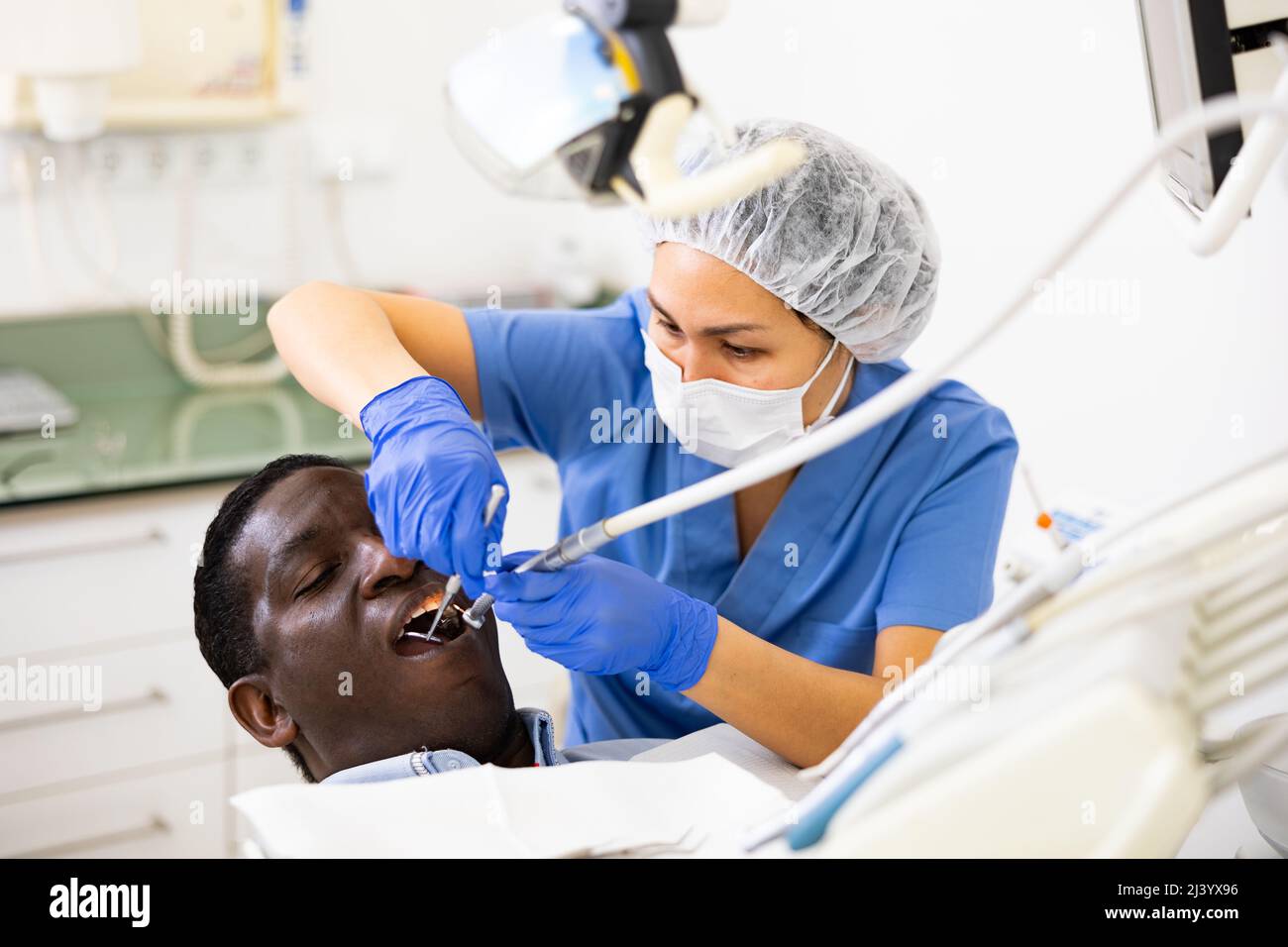 Woman stomatologist treating teeth to patient in dental office Stock