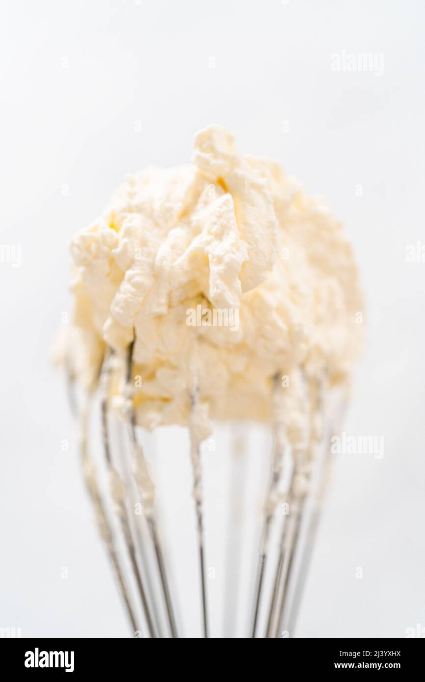 Beating a white cream with a mixer in a metal bowl. Whipped cream. Cream  for the cake Stock Photo - Alamy