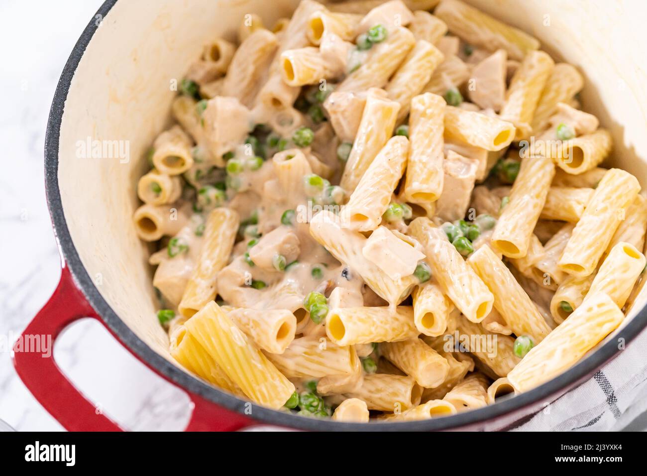 Mixing ingredients in an enameled dutch oven to prepare chicken alfredo