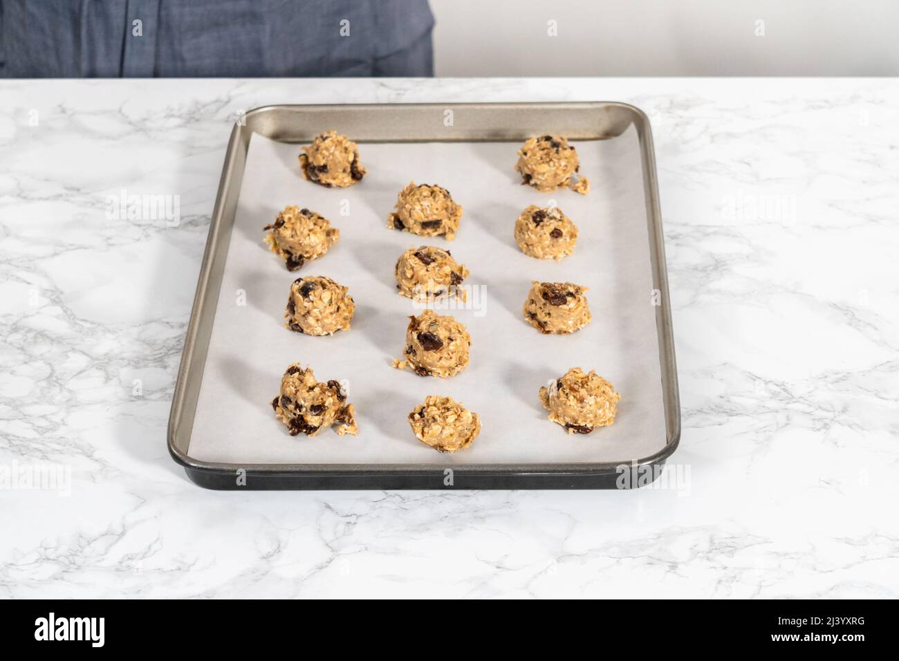 Scooping cookie dough with dough scoop into a baking sheet lined with  parchment paper to bake soft oatmeal raisin walnut cookies Stock Photo -  Alamy