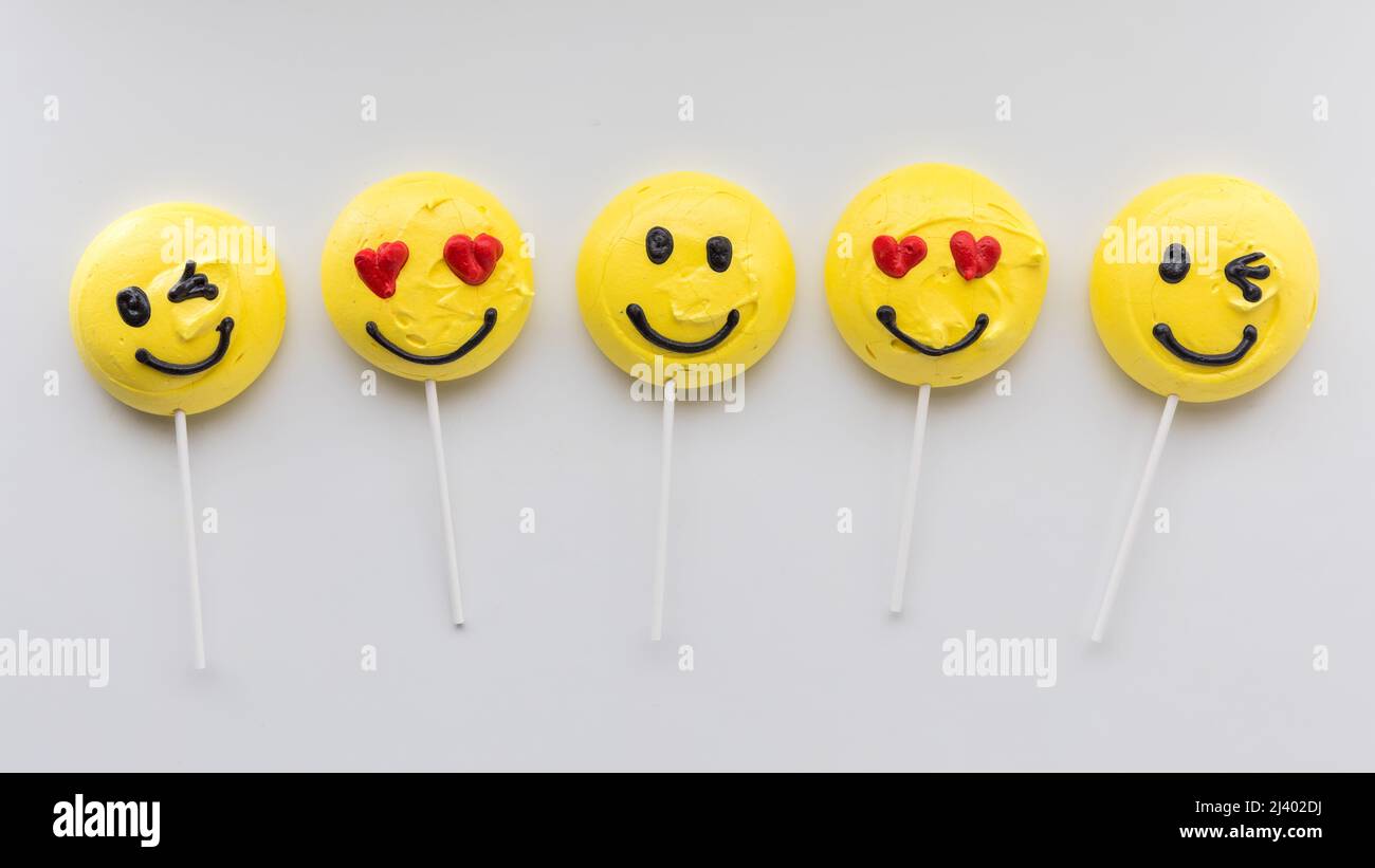 A row of smiley face merengue cookies on lollipop sticks. Stock Photo