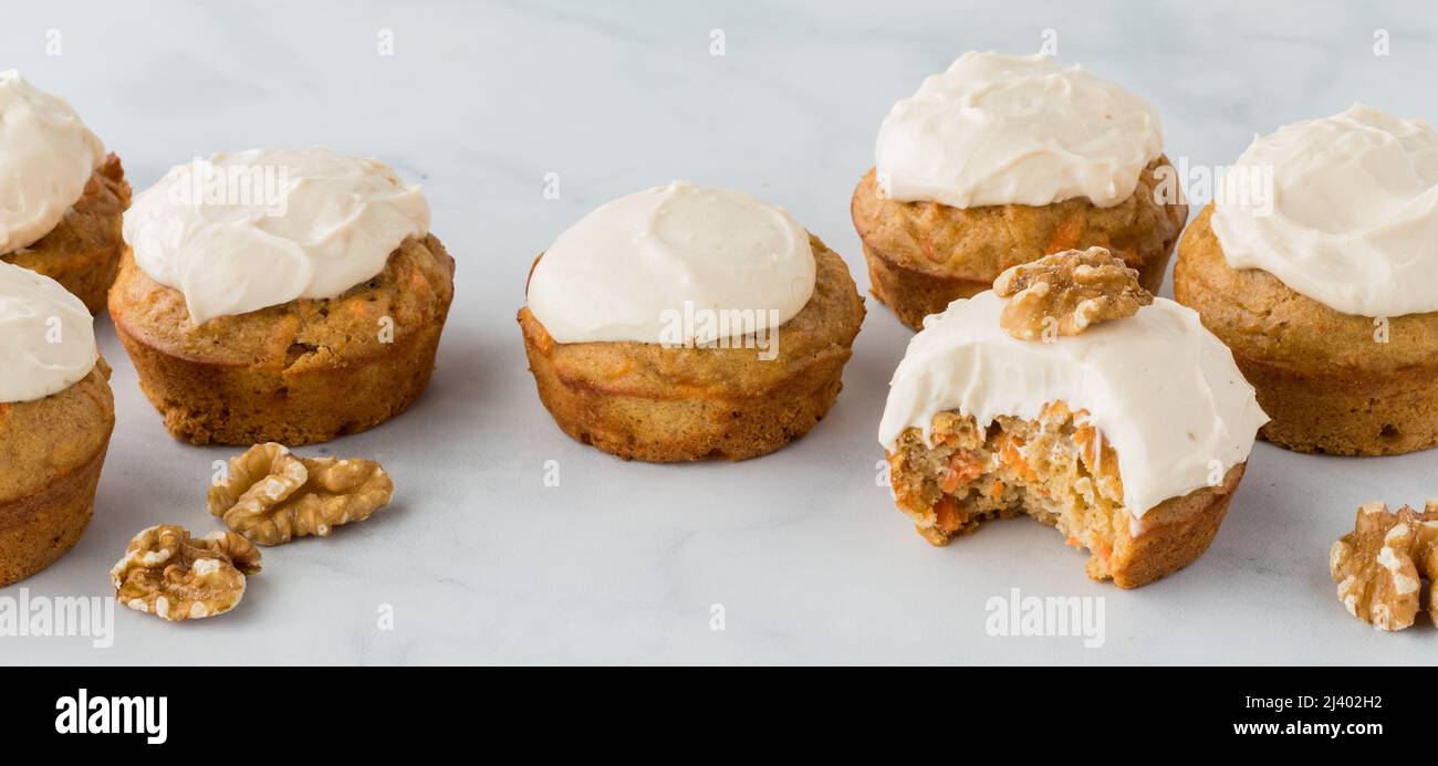 Banner of carrot cake muffins with a bite out of the one in front. Stock Photo