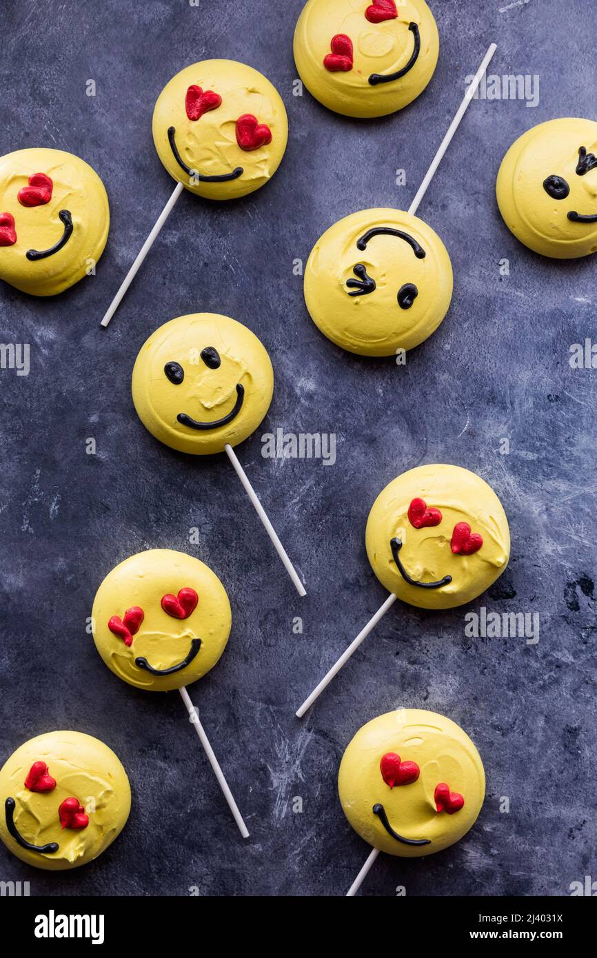Several smiley face emoticon merengue cookies, against a dark background. Stock Photo