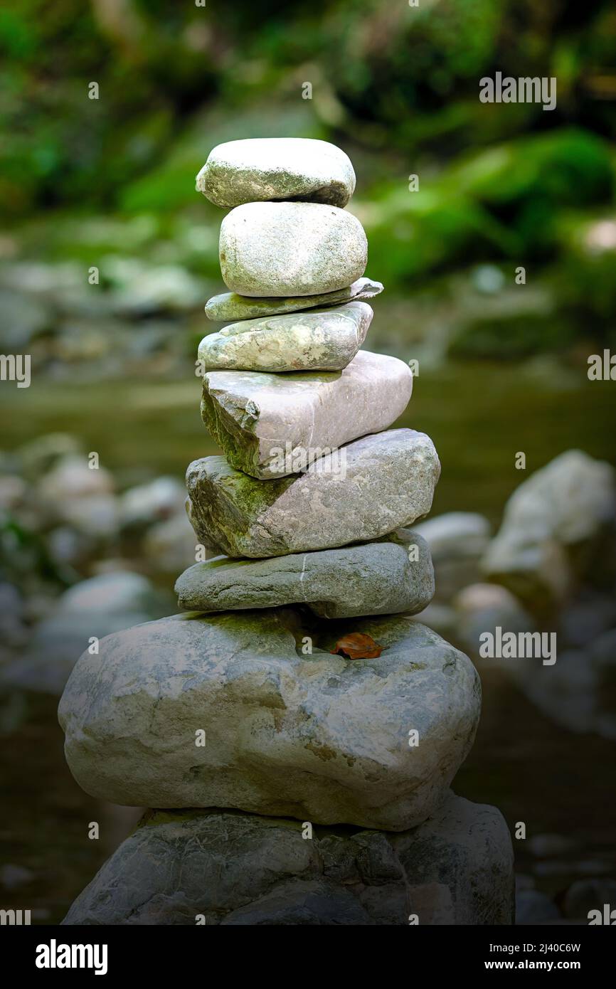 Pile of stacked rocks, in bright sunlight. Rock balancing in a riverbed. Rocks laid flat upon each other to great height. Balanced rocks. Stock Photo