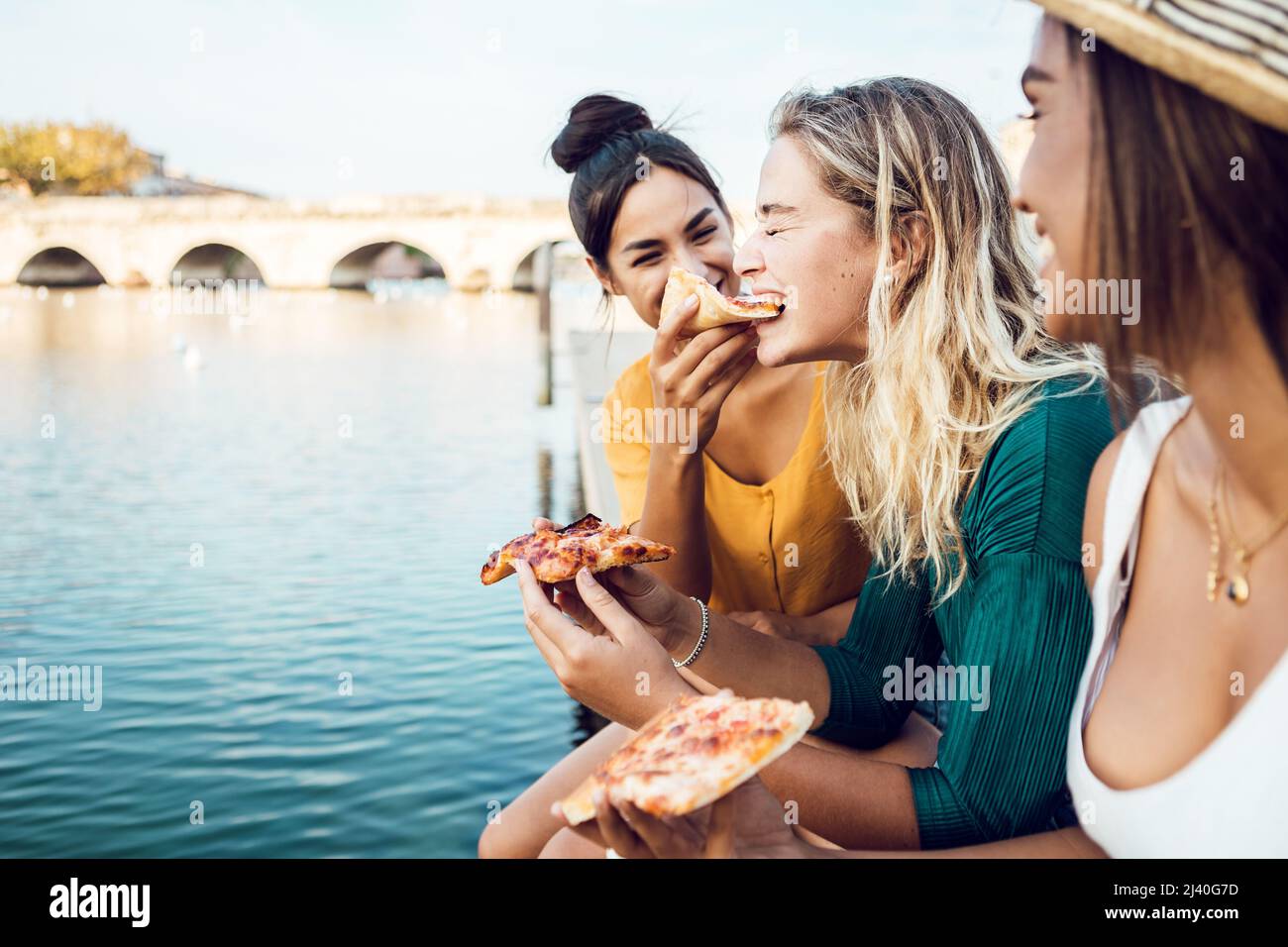Diverse young women friends eating italian take away pizza in city street Stock Photo