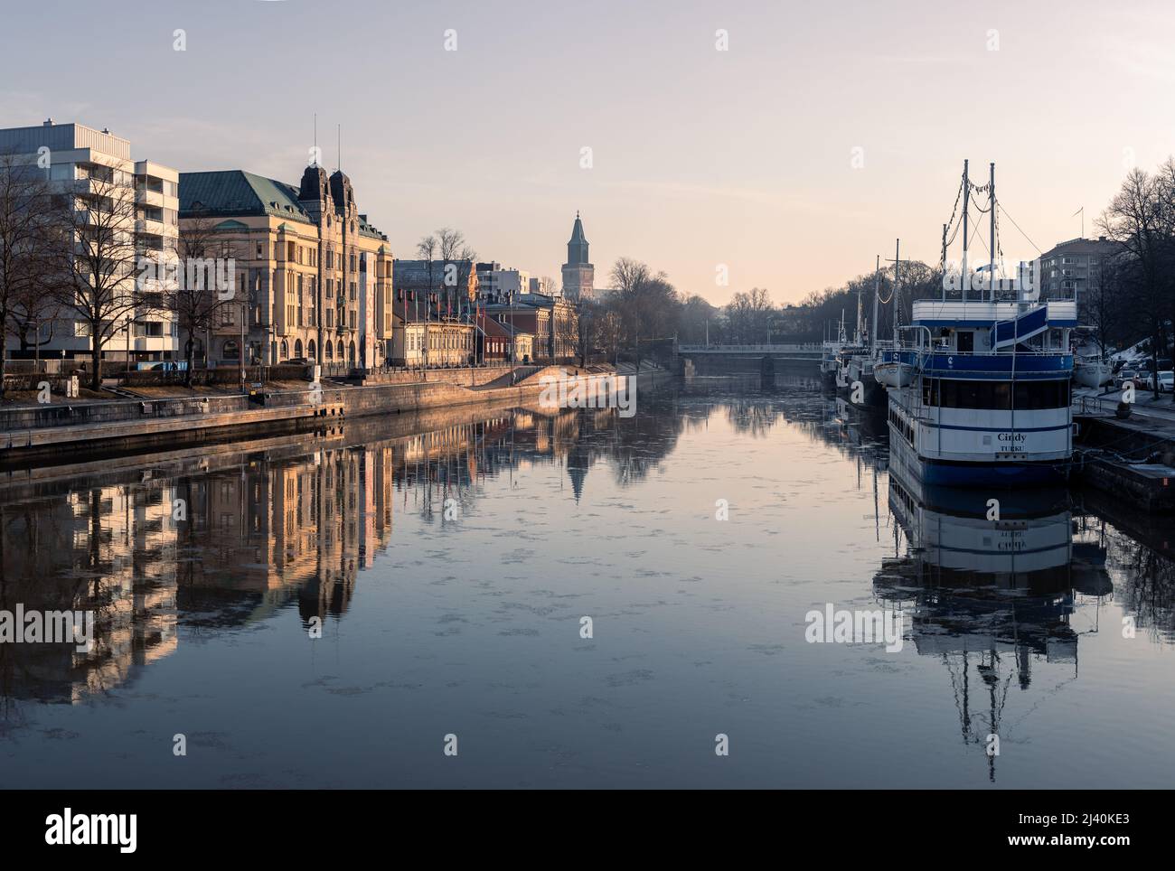 Turku, Finland, March2022: Aurajoki river in the city center area and the restaurant boats with Turku Cathedral in the background in spring Stock Photo