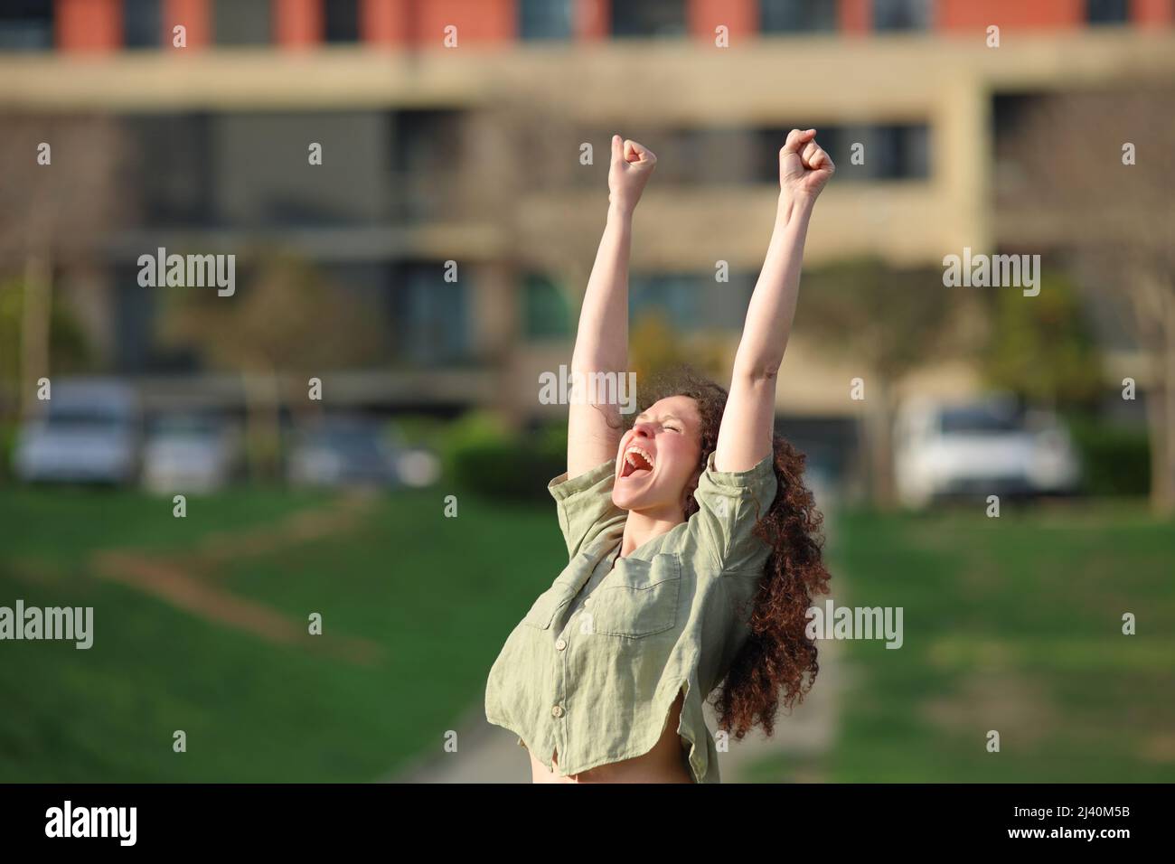 Excited woman raising arms celebrating success in a park Stock Photo ...