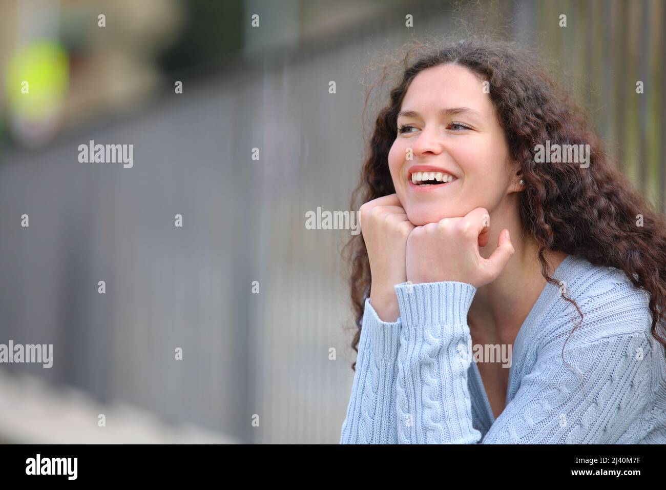 Happy woman laughing and contemplating sitting in the street Stock Photo