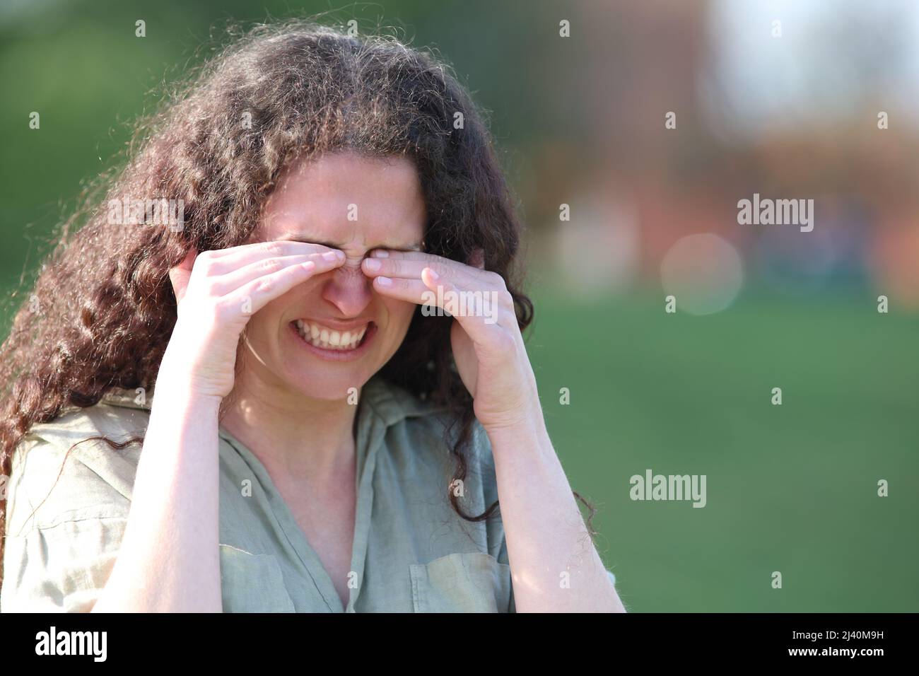 Stressed woman scratching itchy eyes walking in a park Stock Photo