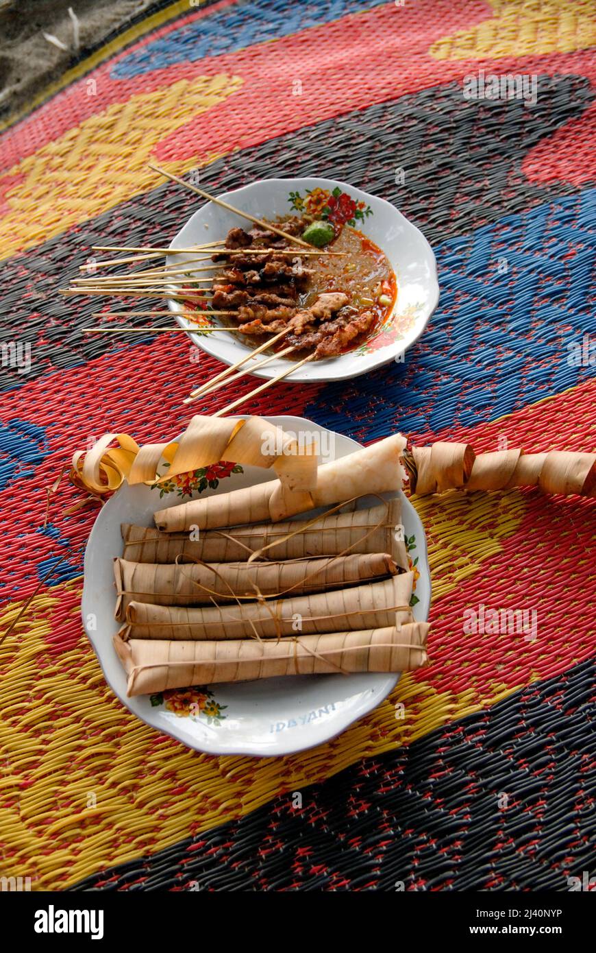 Tasty satay with a spicy sauce eaten with lontong, rice wrapped in palm leaves, on Senggigi Beach. Stock Photo