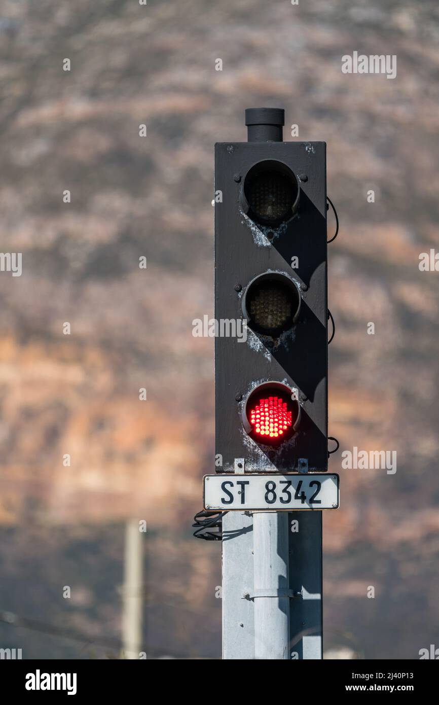 red traffic light on a traffic signal on a railway line against a