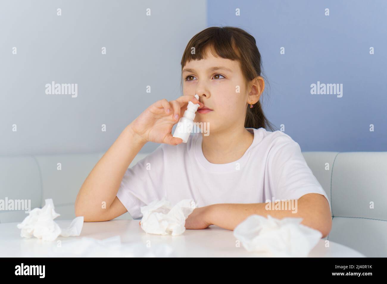 Little girl with runny nose does nasal spray irrigations to stop allergic rhinitis and sinusitis Stock Photo