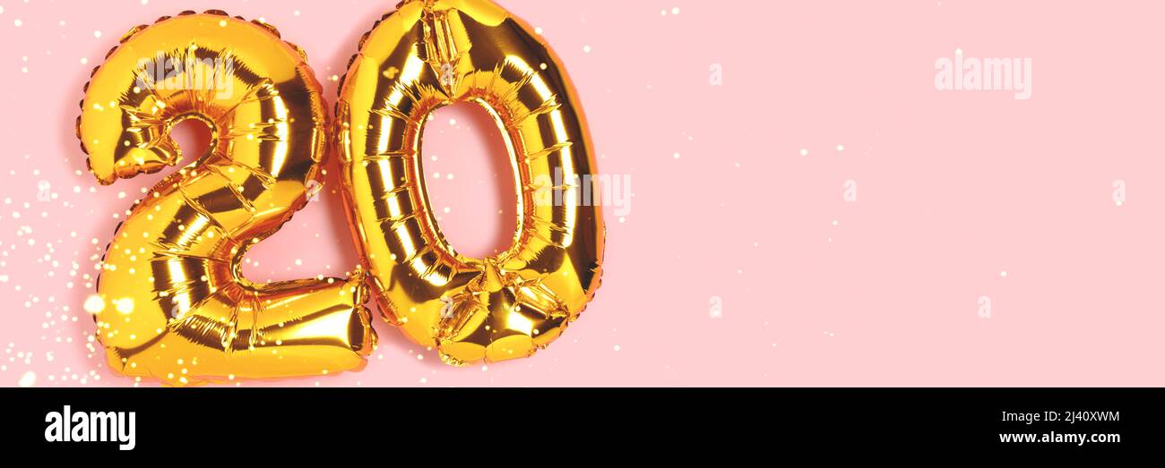 Banner with number 20 golden balloon with copy space. Twenty years anniversary celebration concept on a pink background. Stock Photo