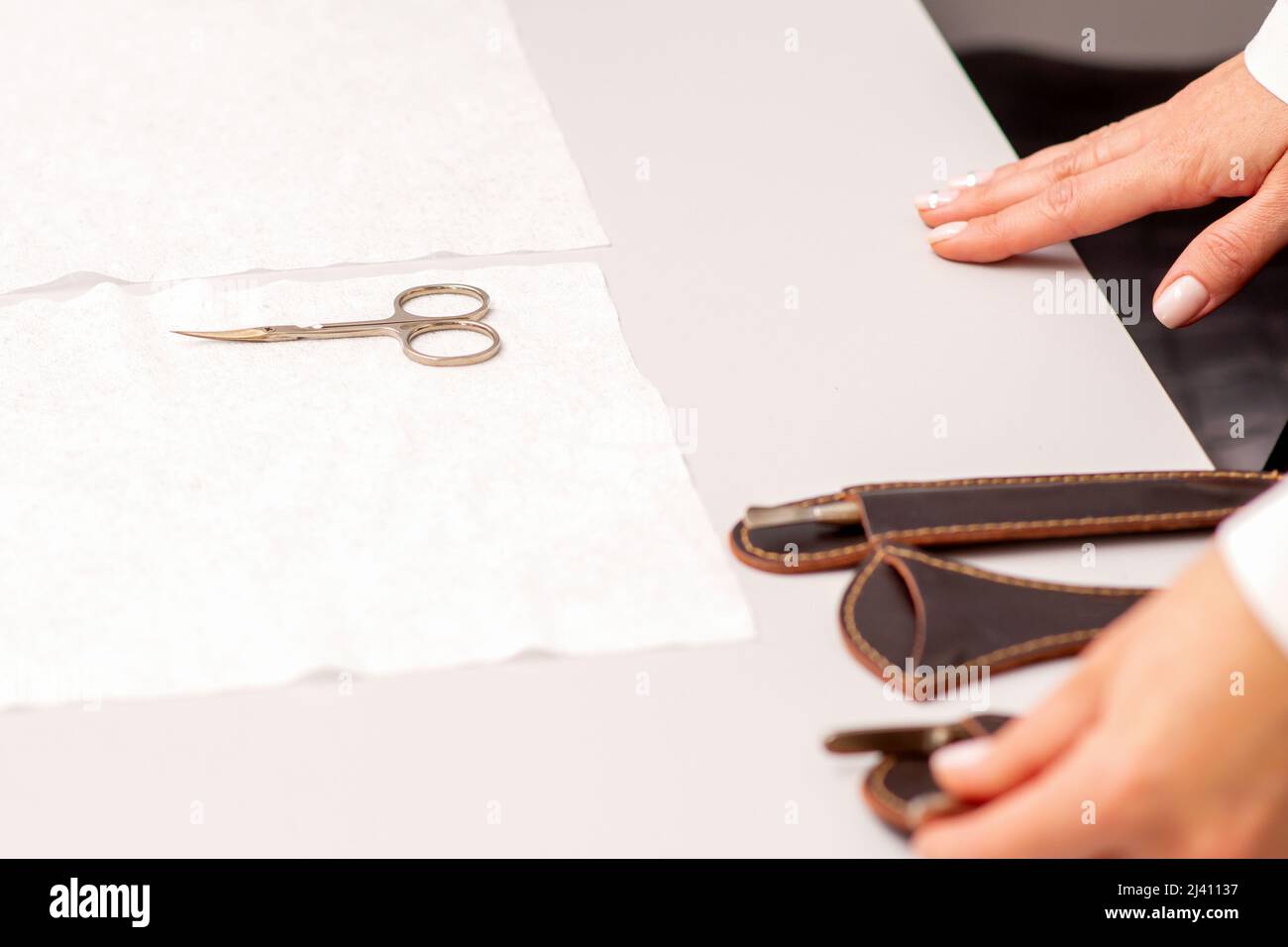 Hands of manicure master prepare nail care tools on a white table Stock Photo