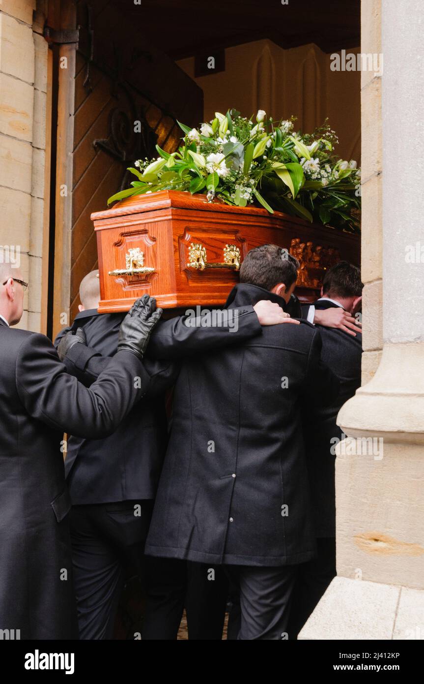 Pall bearers carry a coffin into a church for a funeral mass. Stock Photo