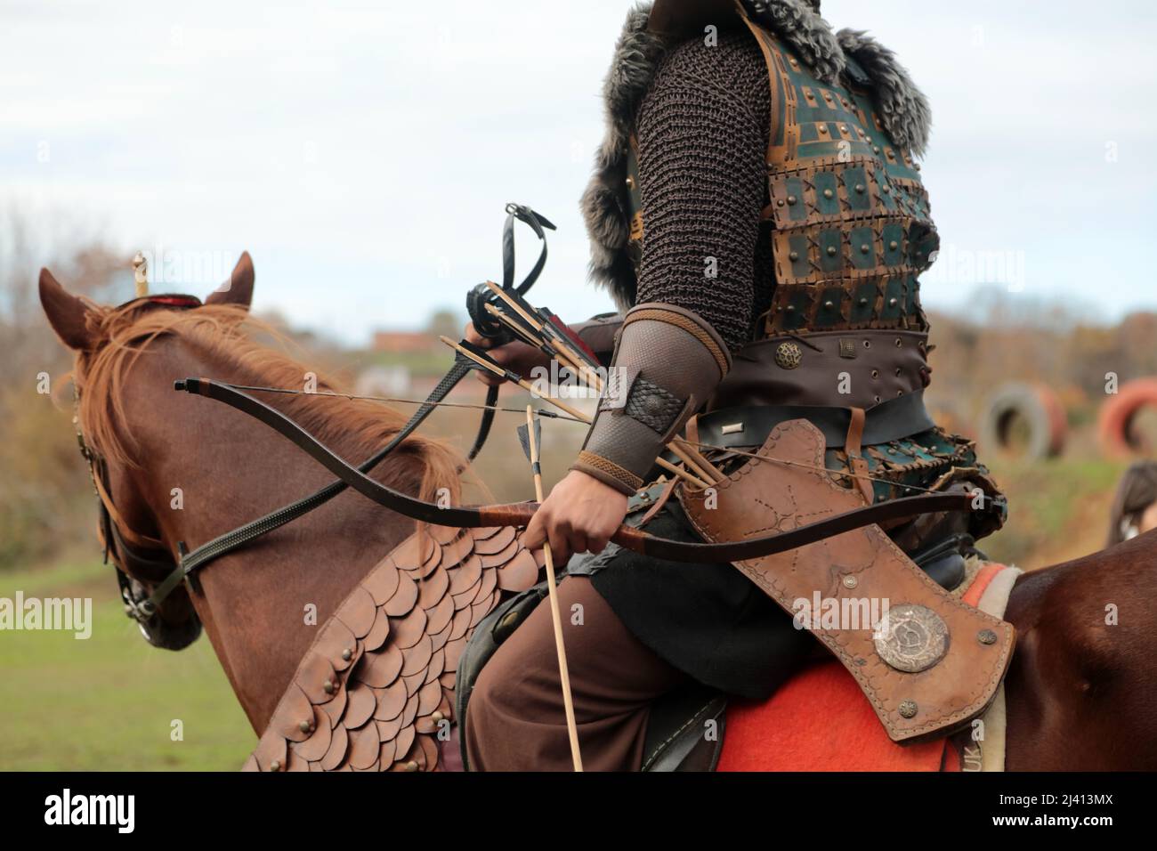 A Turkish soldier in traditional clothing is riding a brown horse. An archer in the old Turkish army. Stock Photo