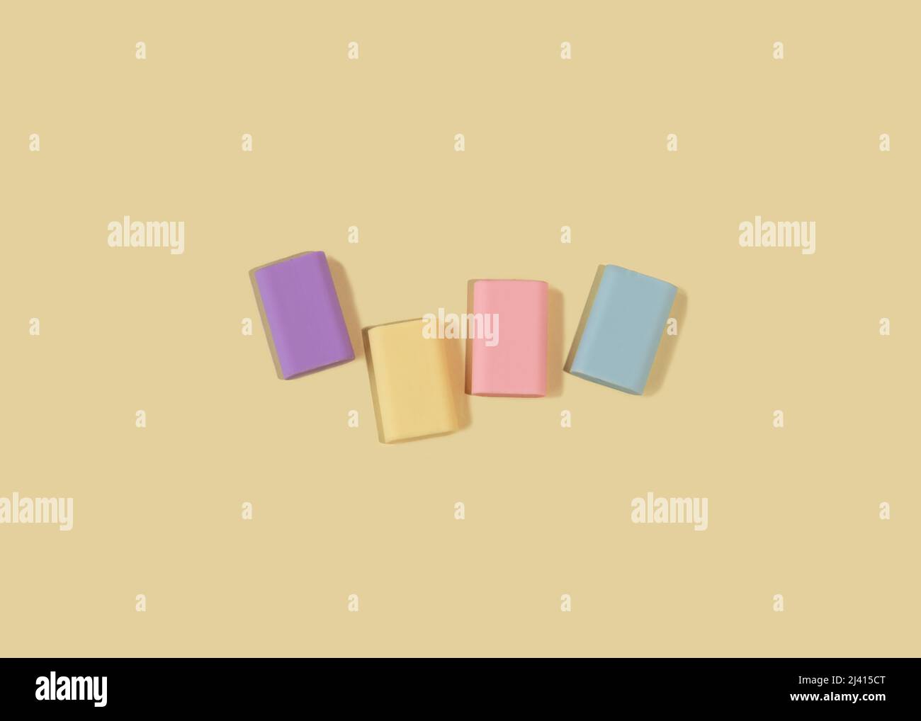 Four rubber erasers in pastel colors on a light yellow background