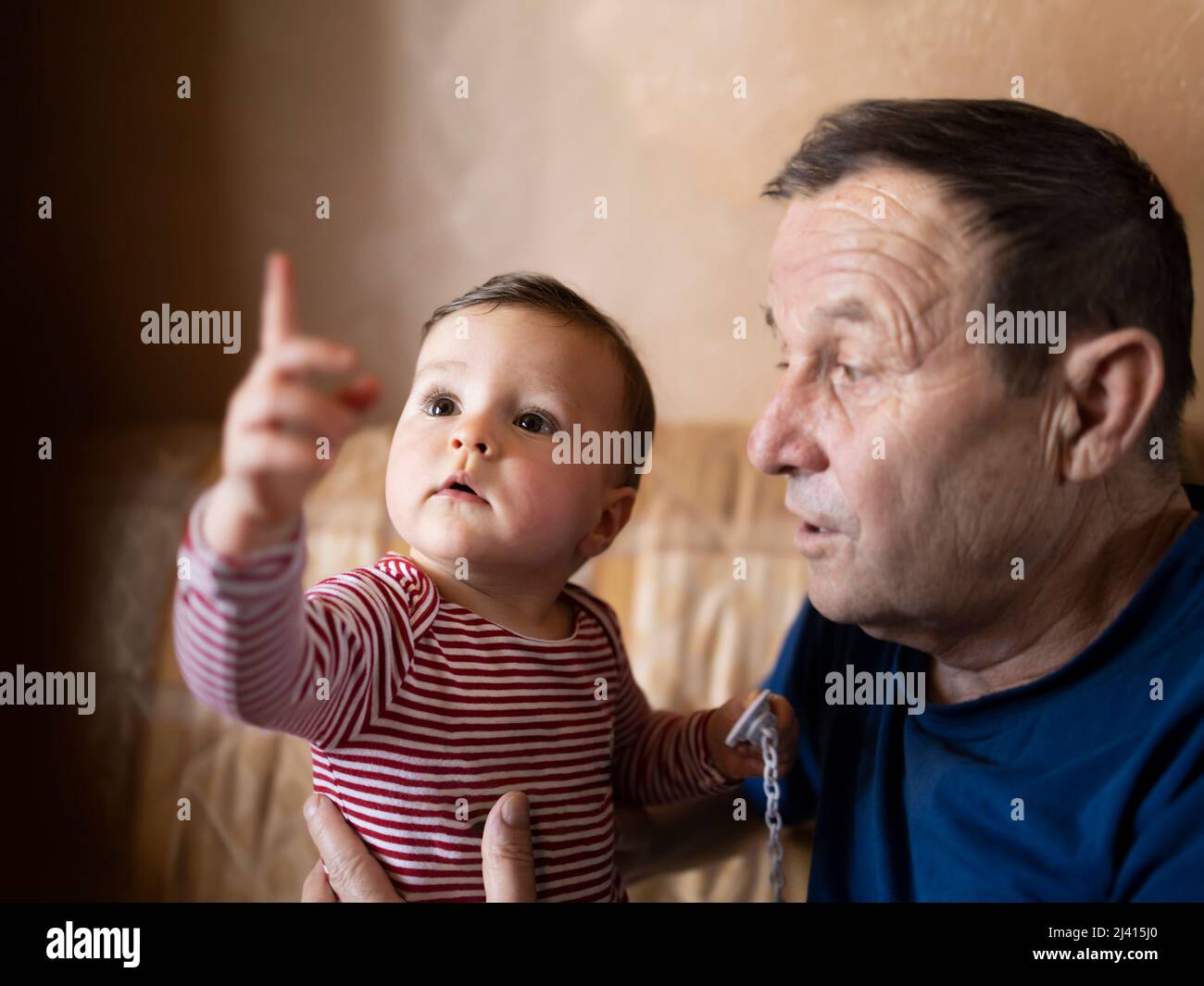 Curious baby exploring her surroundings with her grandpa Stock Photo