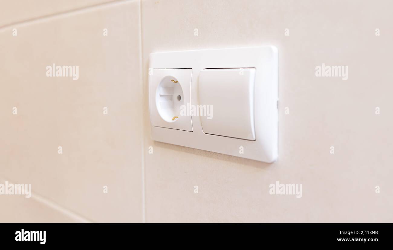 white electrical socket and light switch close-up on a white wall, copy ...