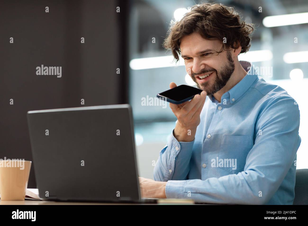 Smiling man working and talking on phone at office Stock Photo