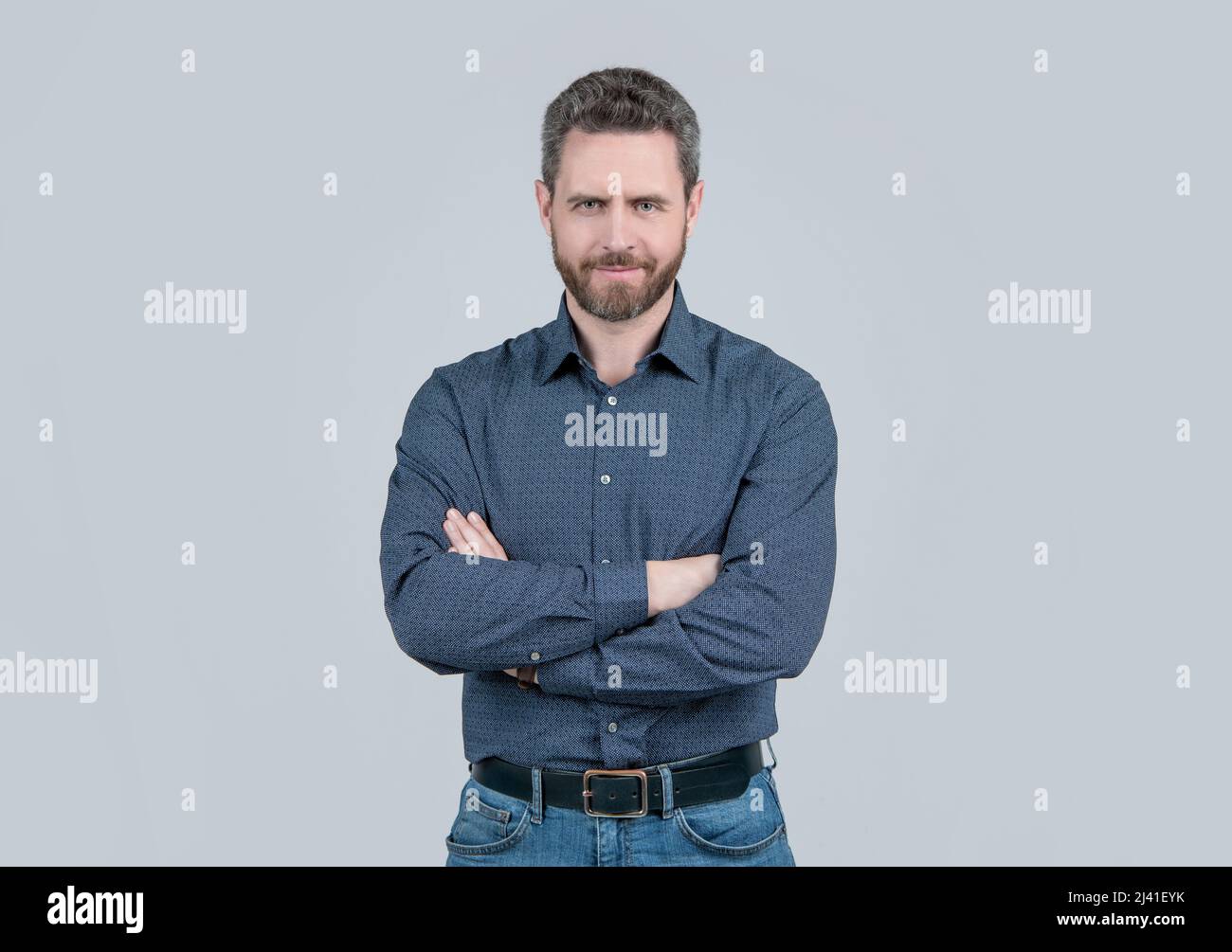 Confident man wear fashion shirt with casual jeans keeping arms crossed grey background, confidence Stock Photo