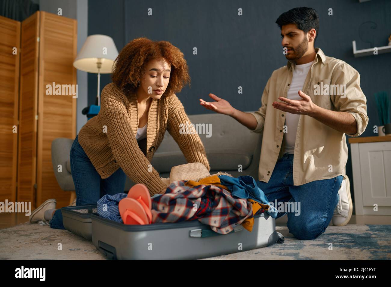 Couple trying to pack belongings into suitcase Stock Photo