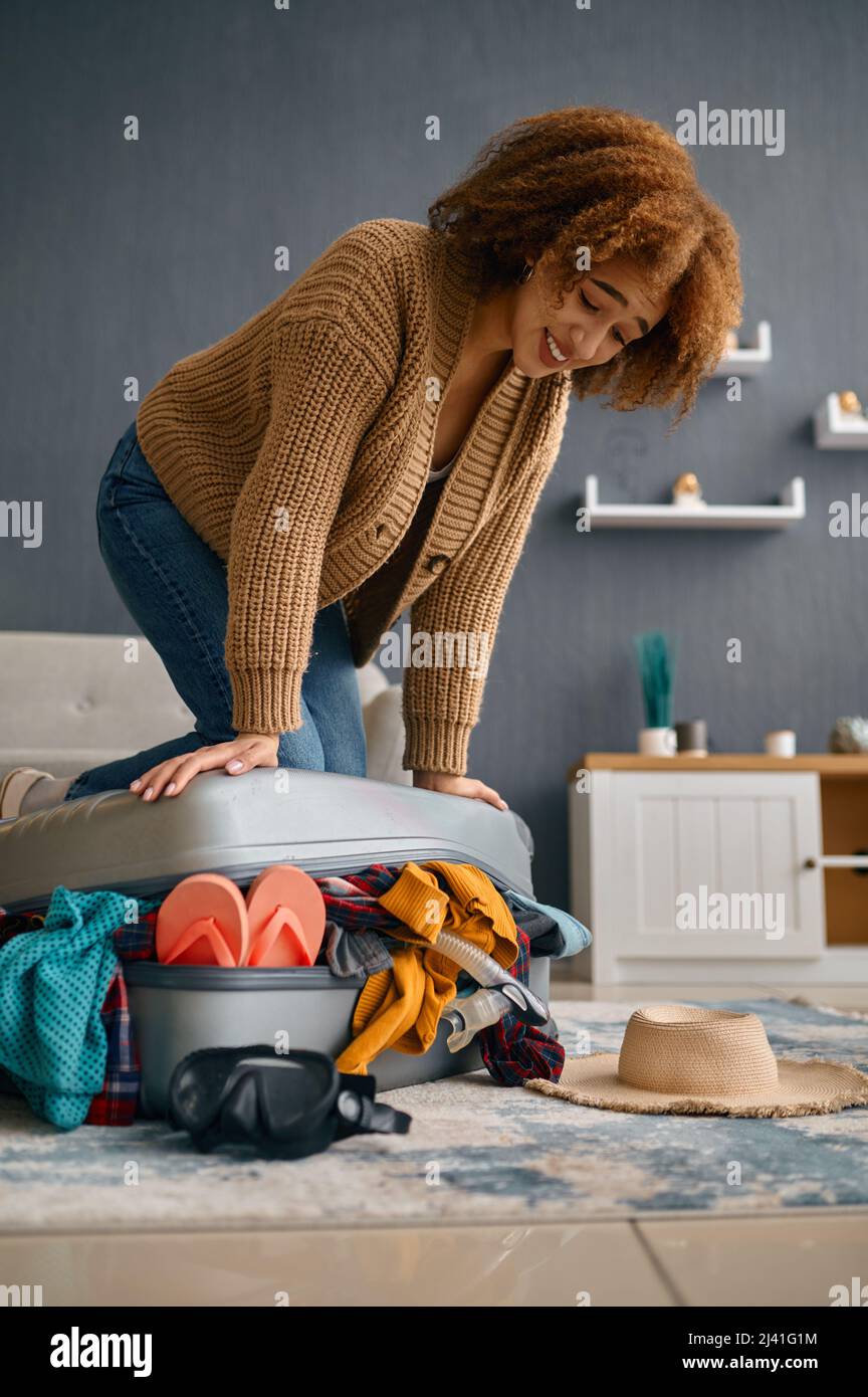 Woman trying to close overload travel suitcase Stock Photo