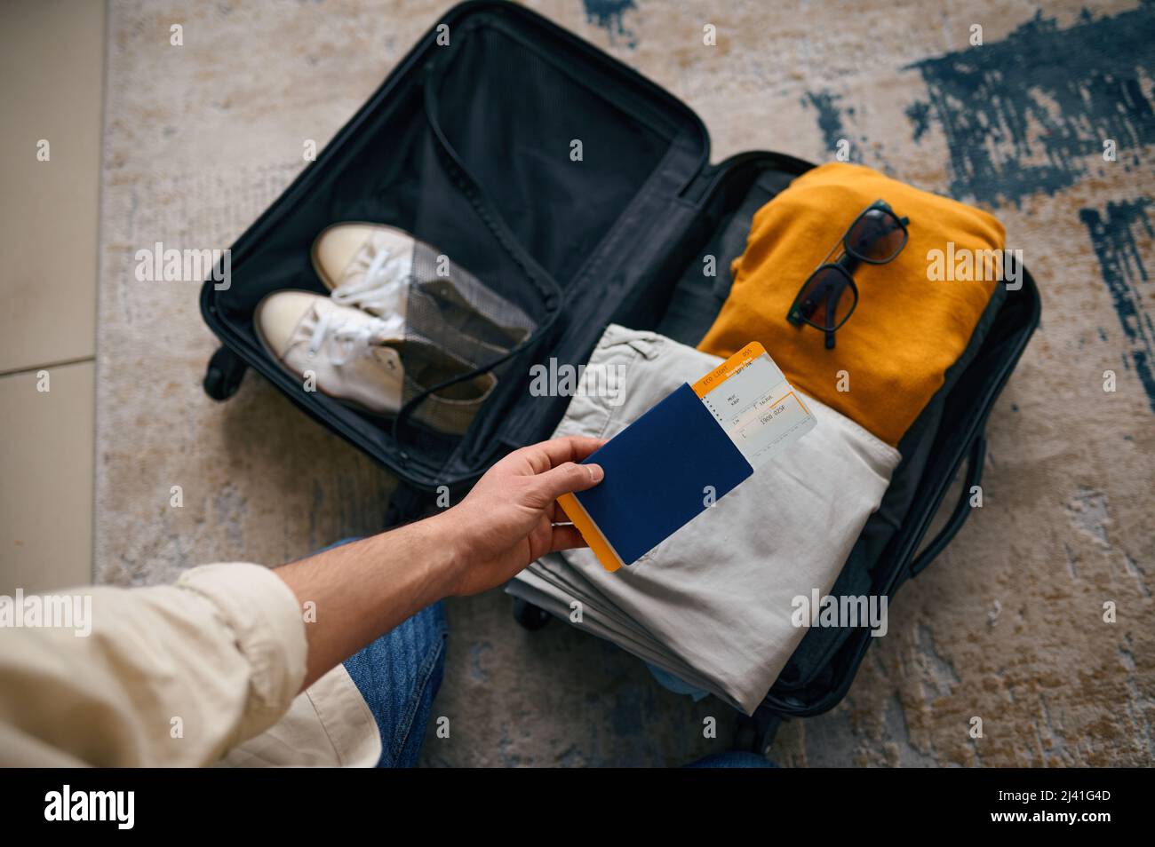 Man with travel ticket and passport at packed suitcase. Stock Photo