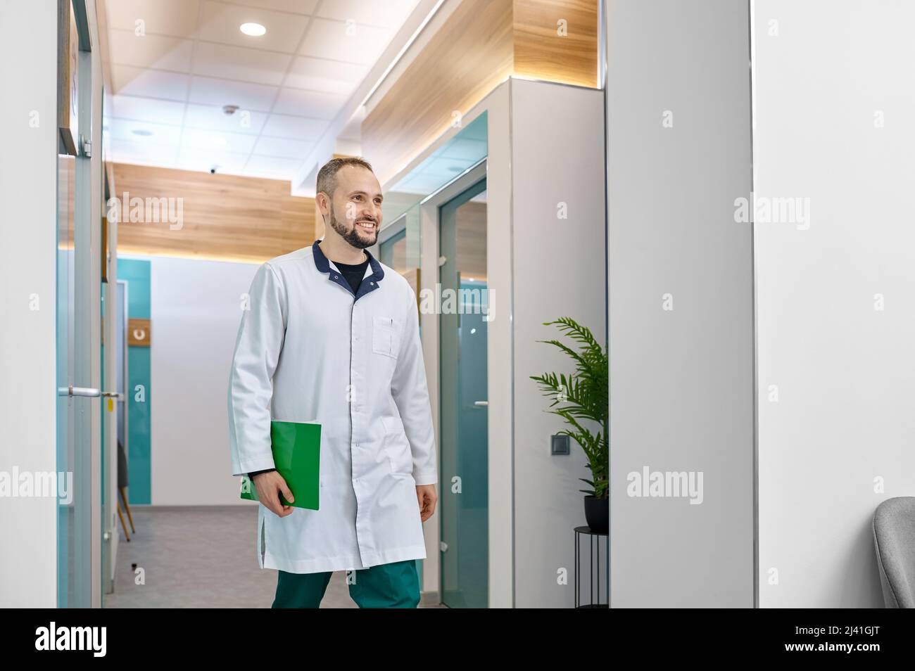 Smiling male doctor walking through hospital hallway Stock Photo