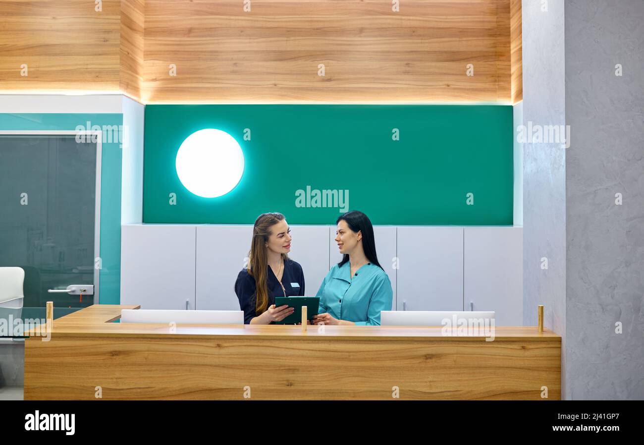 Two female doctors working at reception desk Stock Photo