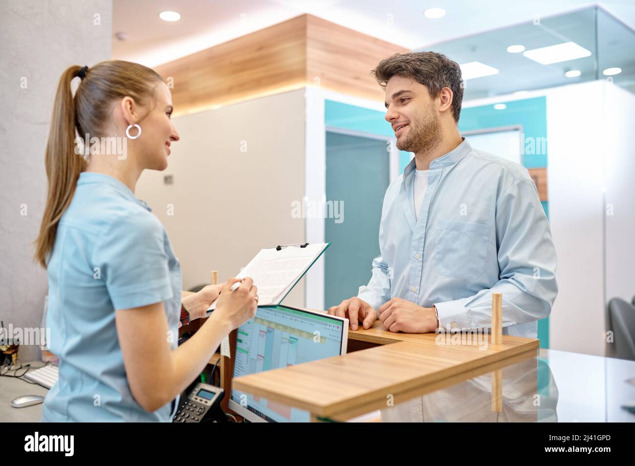 Man talking to professional receptionist in clinic Stock Photo
