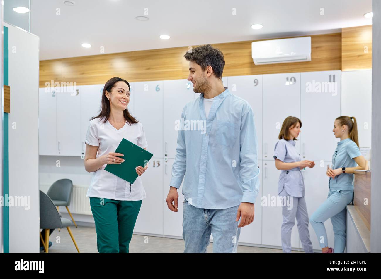 Doctor and patient speaking and walking hallway Stock Photo