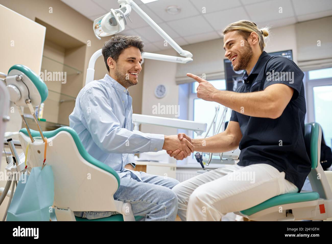 Smiling dentist shaking hand with male patient Stock Photo