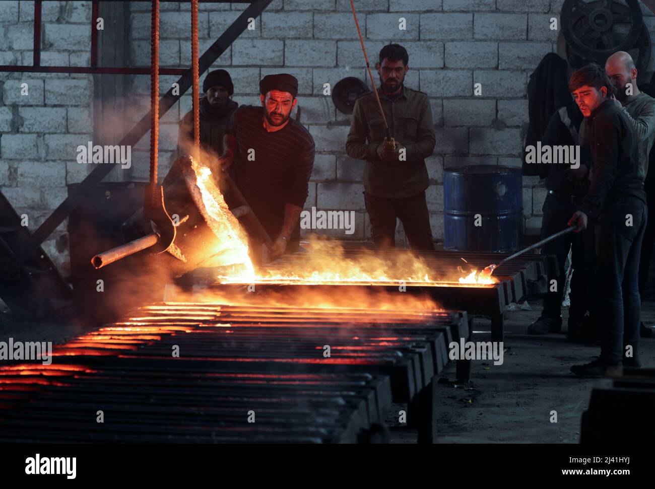 A worker pours melted iron inside a factory at the industrial zone of Syria's rebel-held city of Al-Bab, Syria March 10, 2022. Picture taken March 10, 2022. REUTERS/Khalil Ashawi Stock Photo