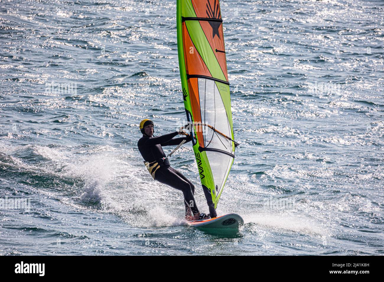 Windsurfer enjoying a fresh westerly wind on Mounts Bay, Cornwall - photographed from public space Stock Photo