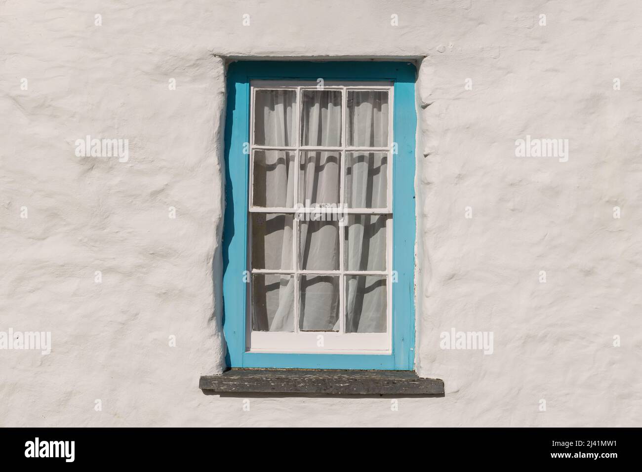 Old wooden sash window frame on a white rendered stone wall. Stock Photo