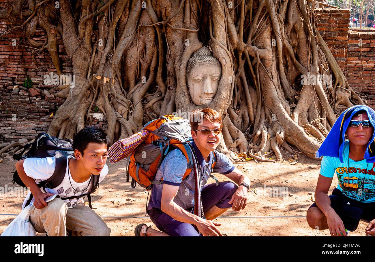 Tourists posing in front of the Buddha Face in the tree in Thailand. Stock Photo