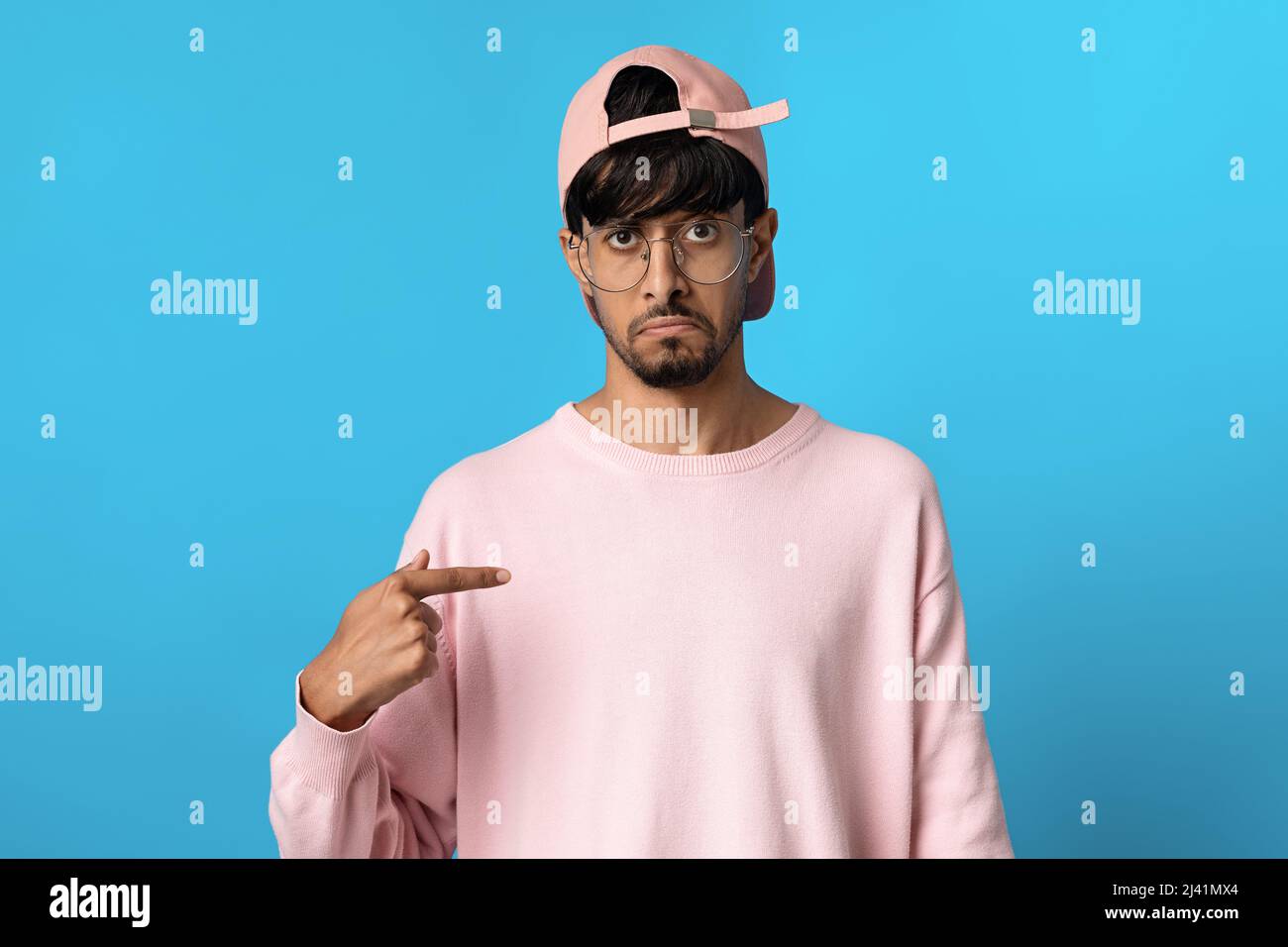 Confused indian guy pointing at himself and looking at camera Stock Photo