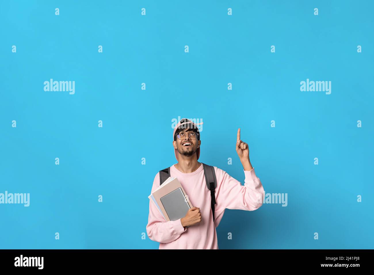 Positive indian guy student pointing up at copy space Stock Photo