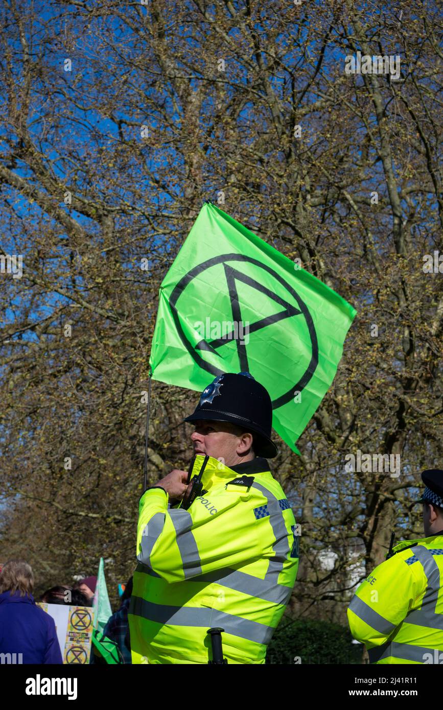 Police officers watching over Extinction Rebellion protesters launching a period of civil disruption in London from the 9 April 2022. XR symbol flag Stock Photo