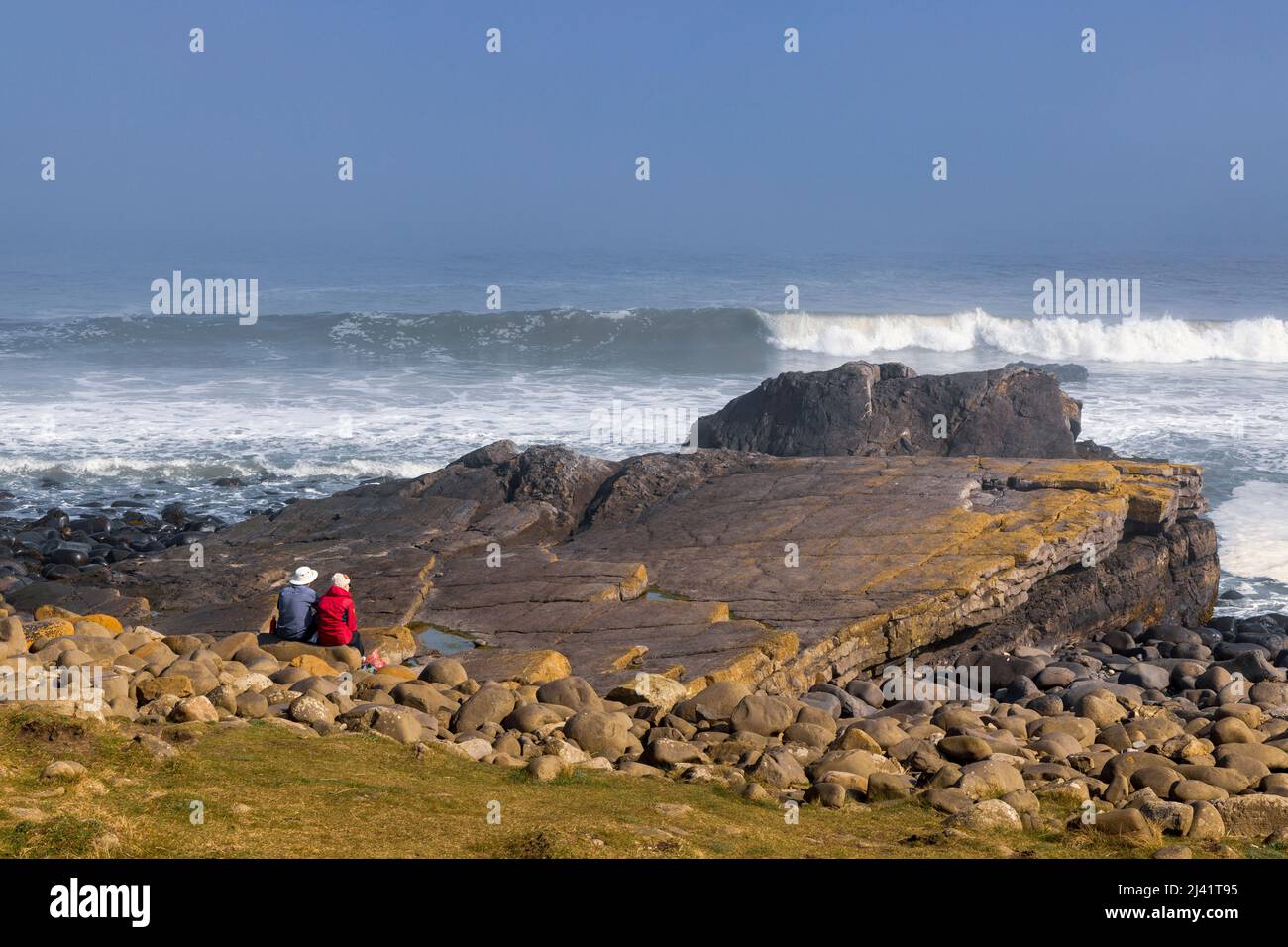 Watching the breaking waves at Greymare Rock on Embleton Beach near Dunstanburgh, Northumberland, England Stock Photo