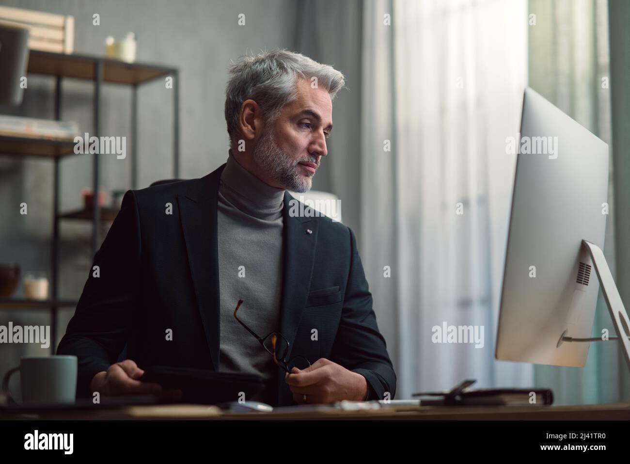 Mature businessman working on computer indoors in office Stock Photo ...