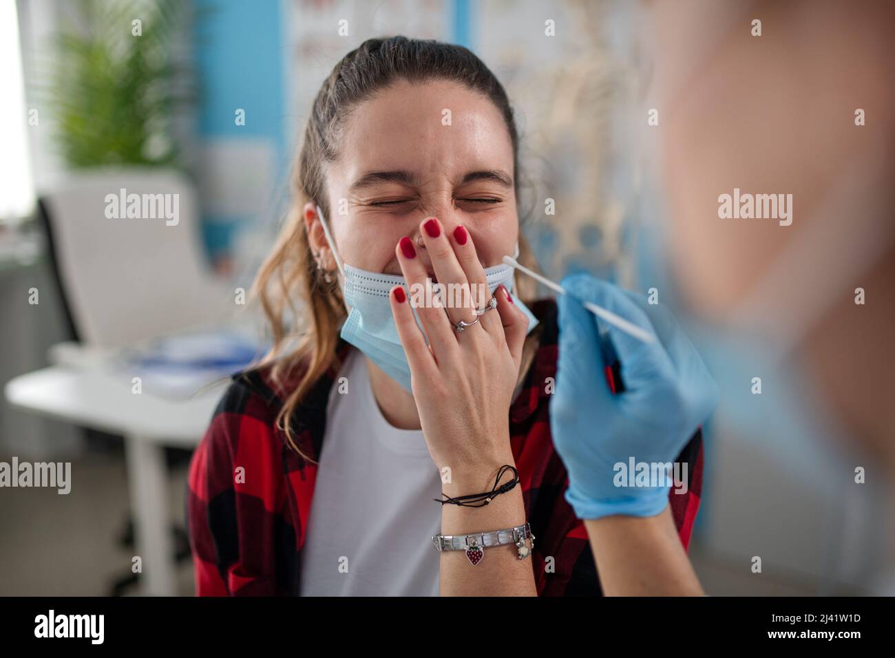 Doctor taking nasal swab test from young woman in clinic. Stock Photo