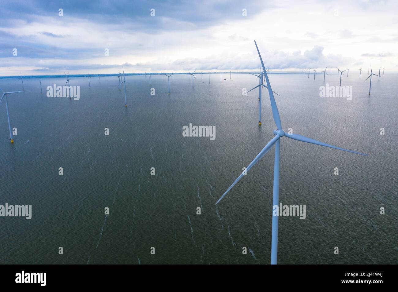 Aerial view of enormous windmills stand in the sea along a dutch sea. Fryslân wind farm, the largest inland wind farm in the world. Afsluitdiijk Stock Photo