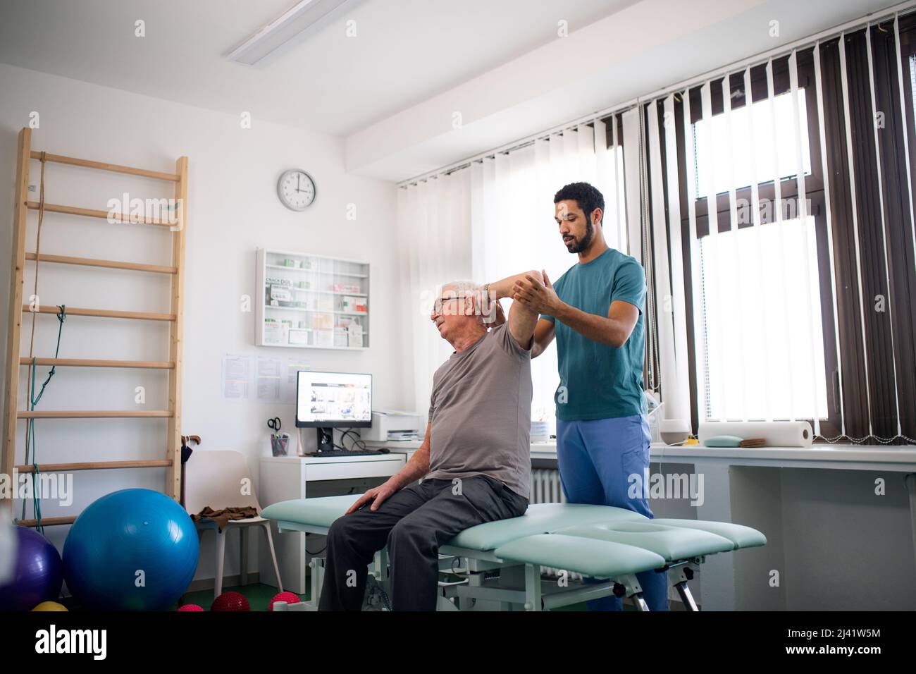 Young physiotherapist exercising with senior patient in a physic room Stock Photo