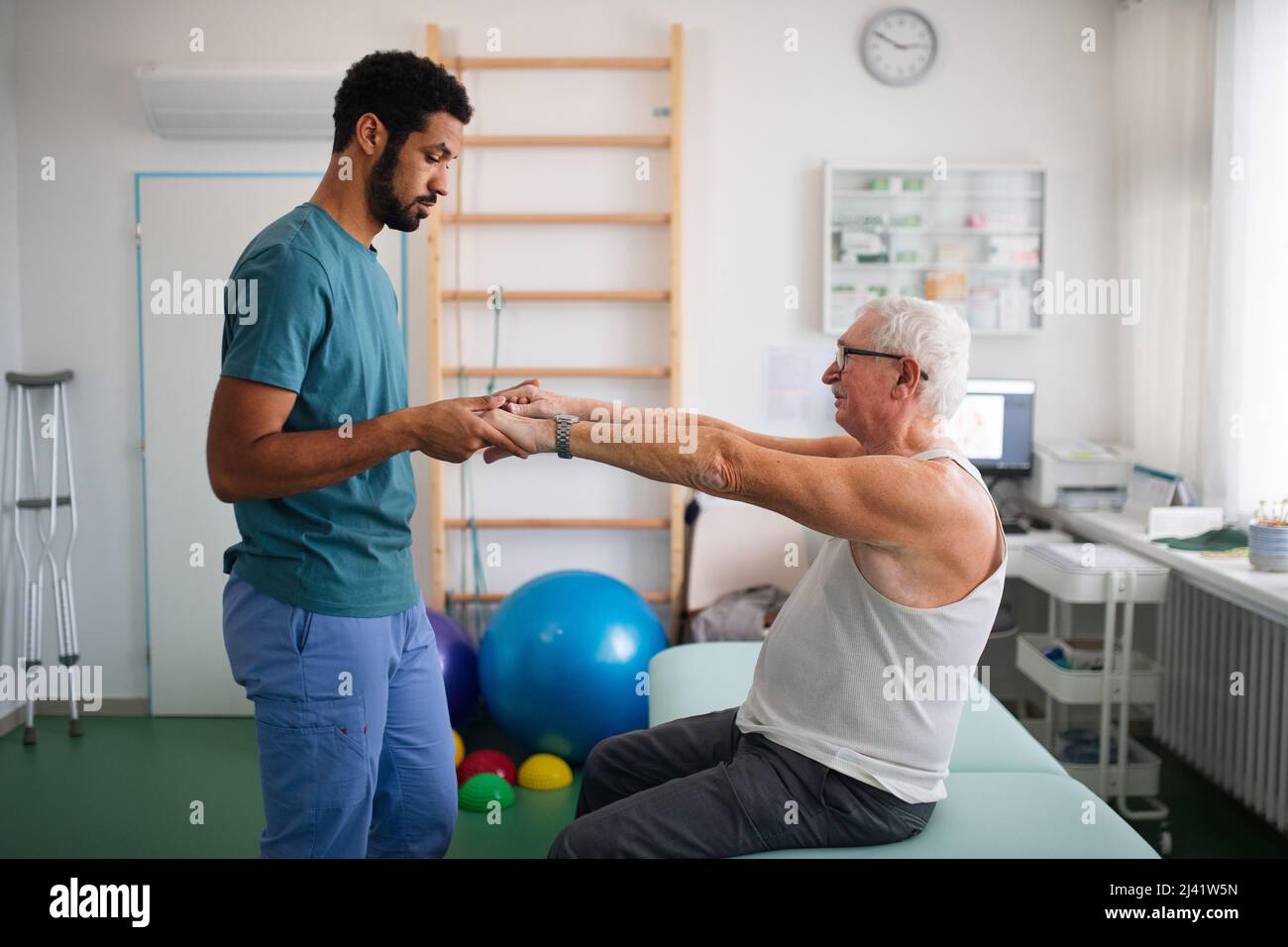 Young physiotherapist exercising with senior patient in a physic room Stock Photo