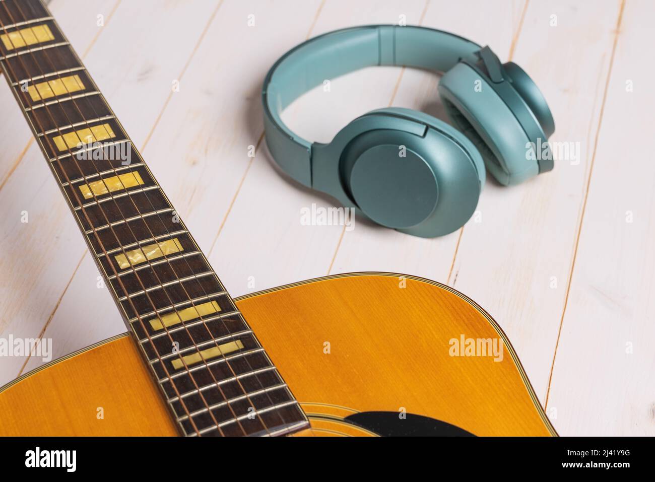 view of guitar and green headphones on wooden background, closeup Stock Photo