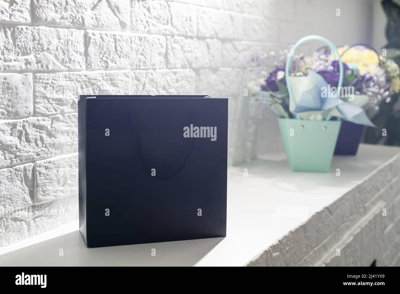 black empty paper bags and bouquets. Blank wall Stock Photo