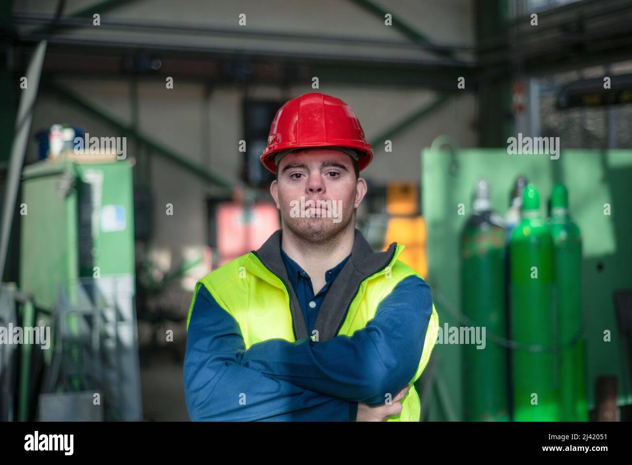 Young man with Down syndrome working in industrial factory, social integration concept. Stock Photo